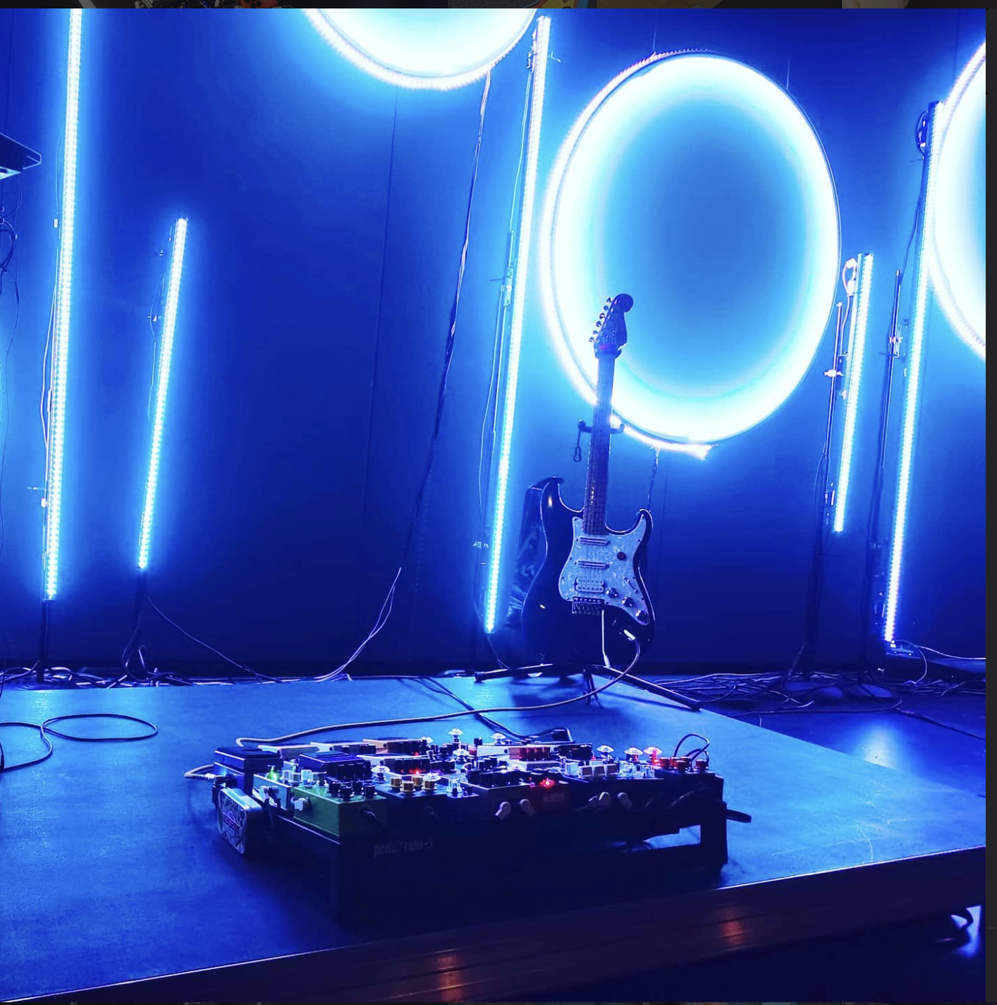 Shieldbearer live stage setup - guitar and pedalboard under blue ring lighting